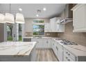 Bright, modern kitchen featuring white cabinets, quartz countertops, gas range, and stainless steel appliances at 575 Dusty Palms Ln, Henderson, NV 89052