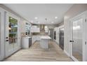 Open concept kitchen features white cabinets, quartz island, stainless appliances, and wood-look flooring at 575 Dusty Palms Ln, Henderson, NV 89052