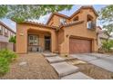 Charming two-story home with a gated entrance, front porch, attached garage, and desert landscaping at 617 Apricot Rose Pl, Las Vegas, NV 89138