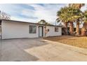 Charming home featuring a clean white exterior, dark window trim and desert landscaping with mature palm trees at 617 Stanford St, Las Vegas, NV 89107