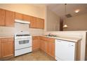 Bright kitchen featuring wood cabinets, white appliances, and tile flooring at 8842 Duncan Barrel Ave # 101, Las Vegas, NV 89178