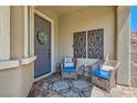 Cozy front porch features decorative metal art, and seating area with blue cushions and a stylish rug at 3434 Boleo Ct, Las Vegas, NV 89141