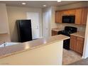 Functional kitchen featuring a black refrigerator, wooden cabinets, and a breakfast bar at 3748 Autumn King Ave, Henderson, NV 89052