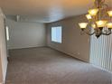 Bright, carpeted living room with large windows and a decorative chandelier at 3748 Autumn King Ave, Henderson, NV 89052