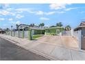 Green home with white horizontal slat fence, spacious driveway, and artificial grass at 4406 Parkchester Cir, Las Vegas, NV 89108