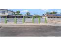 Street view of a green home with a white horizontal slat fence, and solar panels on neighboring rooftops at 4406 Parkchester Cir, Las Vegas, NV 89108