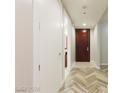 Hallway with wood-look floors leading to a bathroom and dark wood door at 4575 Dean Martin Dr # 2701, Las Vegas, NV 89103