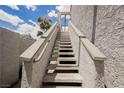 View of a white exterior staircase leading up to condos with blue sky and some vegetation at 5516 Orchard Ln # 0, Las Vegas, NV 89110