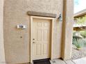 Condo entrance featuring a tan front door with stone accents and a modern light fixture at 6635 Flaminian Ln # 104, North Las Vegas, NV 89084