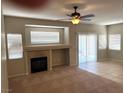 Comfortable living room featuring a warm fireplace, neutral colors, tile and carpet flooring, and ceiling fan at 10195 Queensbury Ave, Las Vegas, NV 89135
