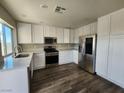 Modern kitchen with stainless steel appliances, white cabinetry, and stylish dark wood flooring at 10400 Beachwalk Pl, Las Vegas, NV 89144