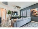 Comfortable living area showcasing gray sofa, modern ceiling fan, sleek floors, and a dark accent wall at 4720 Flower Moon Ave # 101, North Las Vegas, NV 89084