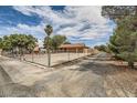 Wide shot showcasing long driveway behind a chain-link fence and gate, and desert landscaping at 5202 Willis St, North Las Vegas, NV 89031