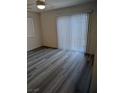 Bright bedroom with wood flooring, a sliding glass door, and a window with white blinds at 6830 Truffle Gray St, Las Vegas, NV 89148