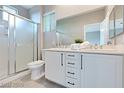 Bathroom with double sinks, white cabinets and a shower with glass door at 7047 Sombra Way, Las Vegas, NV 89113