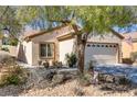 Inviting single-story home with desert landscaping, mature trees, and a two-car garage at 7669 Fieldfare Dr, North Las Vegas, NV 89084