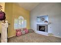 Bright living room featuring a charming fireplace, neutral carpet, ample light from a large window, and colorful chairs at 7728 Whispering River St, Las Vegas, NV 89131