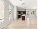 Sunlit open-concept living space with wood-look floors flowing into the kitchen and dining area at 3526 Harbor Tides St, Las Vegas, NV 89147