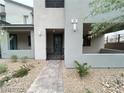 Stylish home entrance with gray stucco walls, low-maintenance landscaping, and a secure gated walkway at 483 Fairview Hills St, Las Vegas, NV 89138