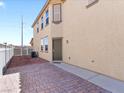 Side view of a tan two-story home with a brick patio and side door at 1124 Aspen Cliff Dr, Henderson, NV 89011