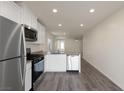 Bright kitchen featuring stainless steel appliances, white cabinets, and an eat-in bar with gray wood-look floors at 2728 Pavehawk Way, Las Vegas, NV 89156