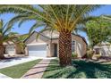 Inviting single-story home featuring desert landscaping with mature palm trees and an attached two-car garage at 5213 Giallo Vista Ct, North Las Vegas, NV 89031