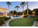 Expansive backyard with a putting green, pool, manicured landscaping, and mature palm trees for outdoor enjoyment at 10243 Cowboys Dream St, Las Vegas, NV 89131