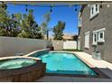 Backyard featuring a sparkling pool and jacuzzi with stone accents, surrounded by a patio and privacy fence at 11278 Tenza Ct, Las Vegas, NV 89141