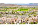Expansive aerial view showcasing a meticulously landscaped neighborhood, complete with a golf course and mountain views at 1887 Hollywell St, Las Vegas, NV 89135