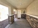 Cozy covered porch with stone accents providing shade and curb appeal to the entrance at 32 Focal Point Ave, North Las Vegas, NV 89031