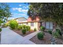Charming townhome featuring a brick accent, mature landscaping, and a walkway leading to the front door at 3925 Torsby Pl, Las Vegas, NV 89119