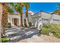 Inviting front entrance with a vibrant red door, mature landscaping, and a spacious three-car garage at 8124 Bay Harbor Dr, Las Vegas, NV 89128