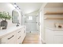 Stylish bathroom with double vanity, glass-enclosed shower, modern fixtures, and floating wood shelves at 8757 Beluga Way, Las Vegas, NV 89117