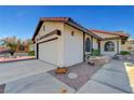Side view of a single-story home featuring stucco siding, a tiled roof, and a two-car garage at 1060 Neil Armstrong Cir, Las Vegas, NV 89145