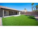 A well-maintained backyard with artificial turf, a covered patio, and a brick wall, perfect for relaxation at 11119 River Hills Ln, Las Vegas, NV 89135