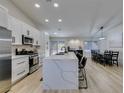 Modern kitchen boasts an expansive island, stainless appliances, and an adjacent dining area with seating for eight at 1673 Golden Vista Dr, Las Vegas, NV 89123