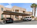 Beige condo building featuring covered parking, landscaped grounds, and palm trees at 2232 Aspen Mirror Way # 202, Laughlin, NV 89029