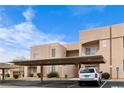 Beige condo building featuring covered parking, landscaped grounds, and clear blue sky at 2232 Aspen Mirror Way # 202, Laughlin, NV 89029