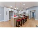 Bright kitchen featuring a large island with seating, white cabinets, modern lighting, and wood-look flooring at 6324 Eugene Ave, Las Vegas, NV 89108