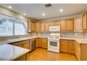 Bright kitchen featuring wooden cabinets, white appliances, tile backsplash, and a window over the sink at 10009 Netherton Dr, Las Vegas, NV 89134