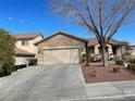 View of the home featuring a two car garage, desert landscaping and a covered porch with patio furniture at 1018 Snow Bunting Ct, Henderson, NV 89002