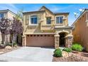 Two-story home featuring a two-car garage, stone accents, balcony, and landscaped front yard at 10230 Danskin Dr, Las Vegas, NV 89166