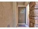 View of the home's front door with stone accents, 'Welcome' mat, and decorative wreath at 10230 Danskin Dr, Las Vegas, NV 89166