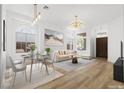 Bright living and dining area with contemporary furnishings, light wood floors, and modern light fixtures at 10540 Beachwalk Pl, Las Vegas, NV 89144