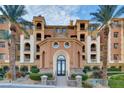 Upscale building with well-manicured landscaping, arched entrance, balconies, and decorative stonework at 15 Via Mantova # 401, Henderson, NV 89011