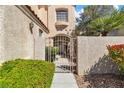 Close-up of gated walkway leading to the arched doorway with textured walls and mature landscaping at 1825 Derbyshire Dr, Las Vegas, NV 89117