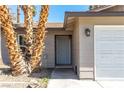 A close-up of the front door and two-car garage, painted in neutral tones with desert landscaping at 3143 La Mesa Dr, Henderson, NV 89014