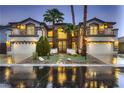 Beautiful home at dusk features a well-lit three-car garage and meticulously landscaped front yard with palm trees at 386 Wiseton Ave, Las Vegas, NV 89183
