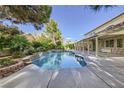 Lush backyard oasis with a sparkling pool, stone waterfall feature, covered patio, and beautiful landscaping at 386 Wiseton Ave, Las Vegas, NV 89183