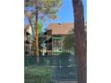 Two story townhouse with green awnings and balconies surrounded by mature trees and a green gate at 520 Elm Dr # 202, Las Vegas, NV 89169